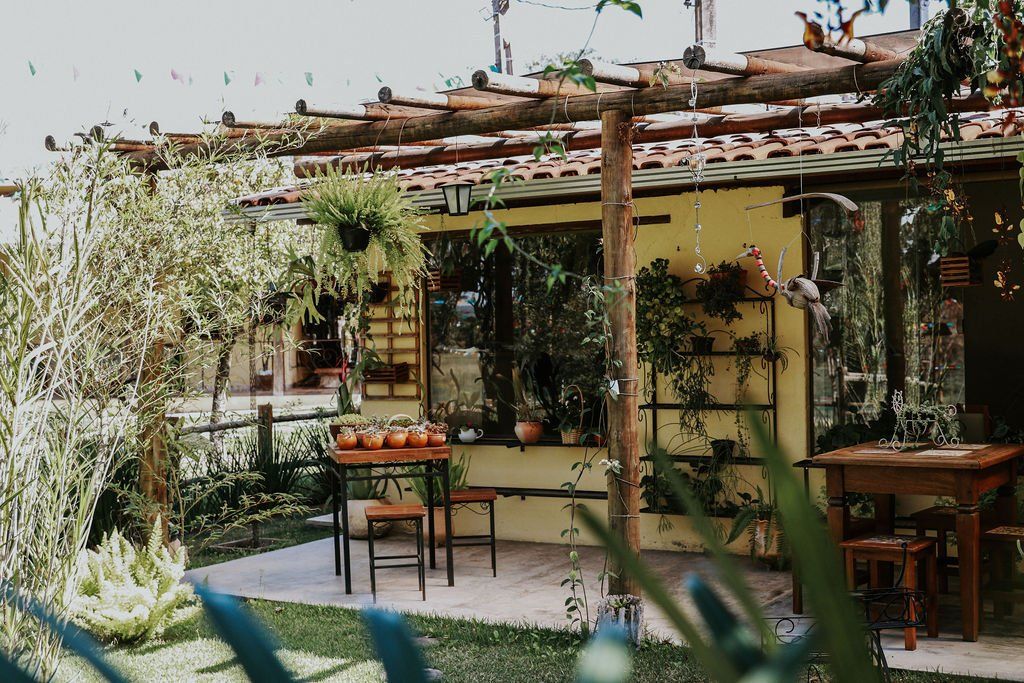 Uma casa com uma pérgola e uma mesa e cadeiras na frente dela.