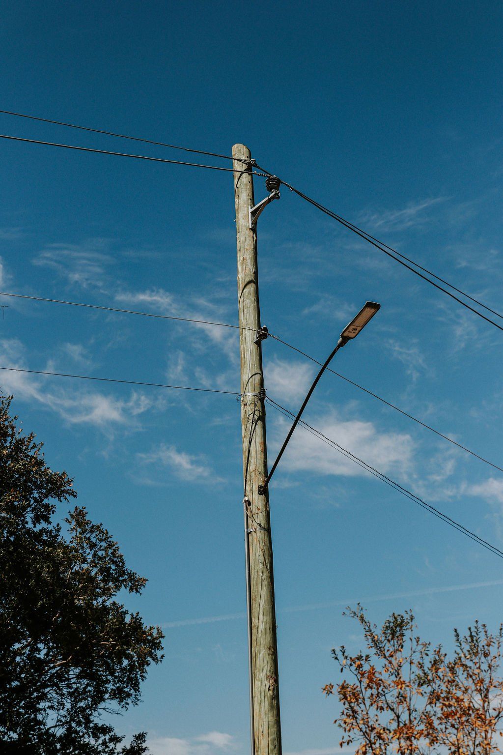 Um poste de madeira com fios telefônicos presos a ele contra um céu azul.