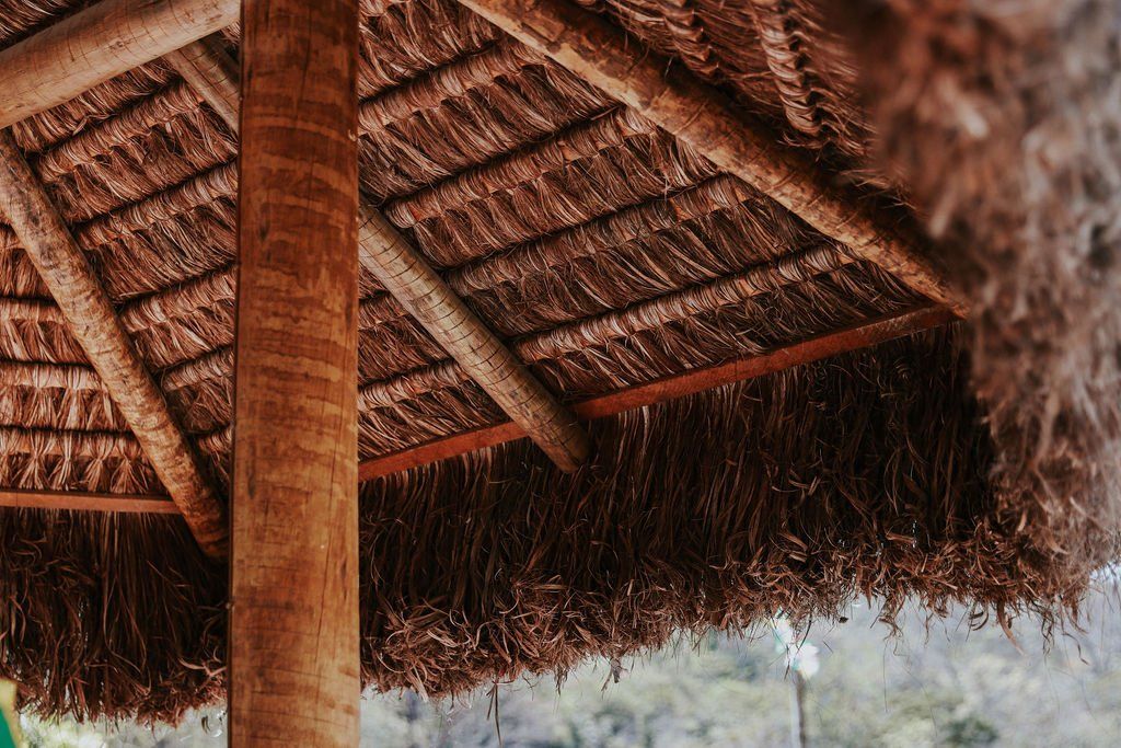 Um close de um telhado de palha com um poste de madeira.