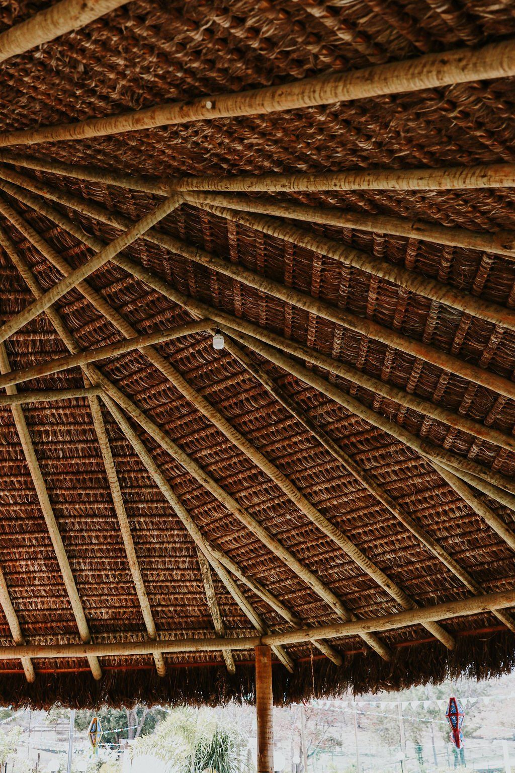 O telhado de uma cabana feita de palha e vigas de madeira.