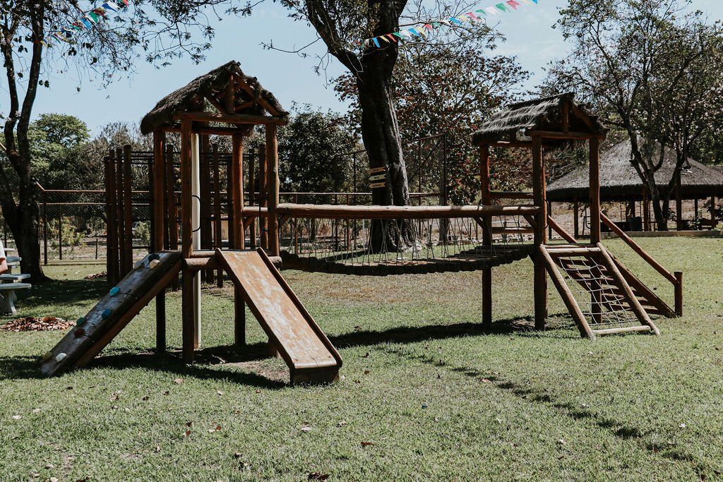 Um playground de madeira está situado no meio de um campo gramado.