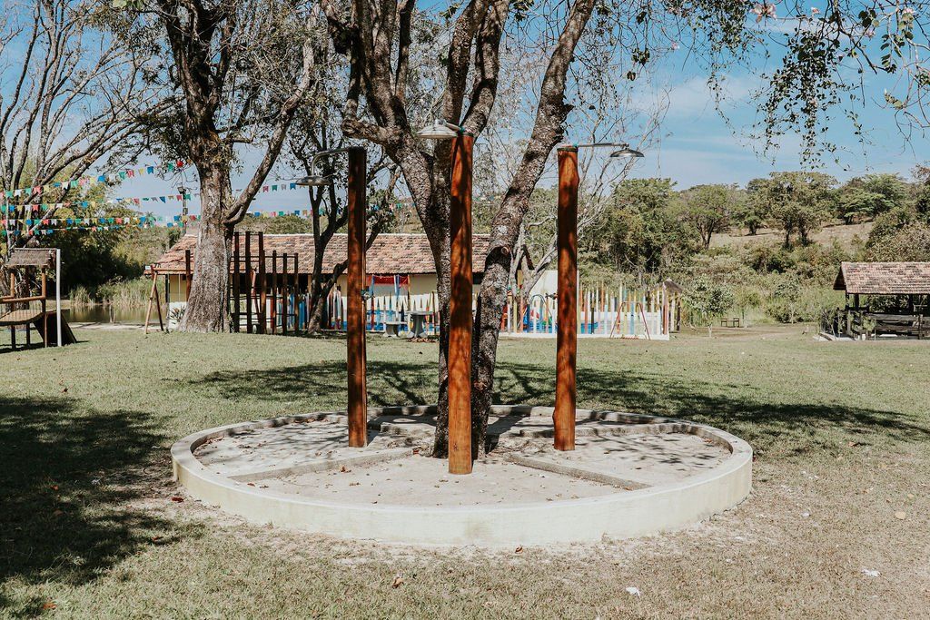 Um grupo de postes de madeira dispostos em círculo ao redor de uma árvore.