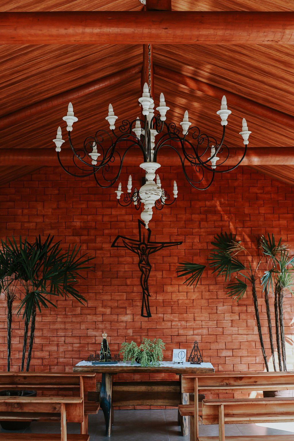 Uma igreja com uma cruz na parede e um lustre pendurado no teto.