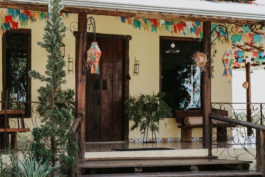 Uma casa amarela com uma varanda de madeira e uma porta de madeira