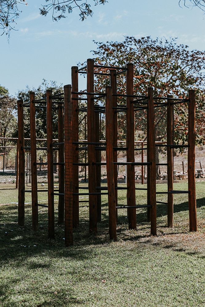 Uma barra de madeira em um parque com árvores ao fundo.