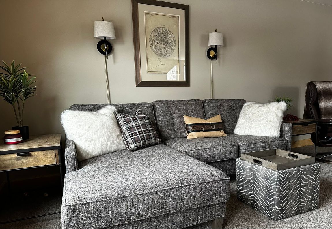 A living room with a couch , ottoman , table and chairs.