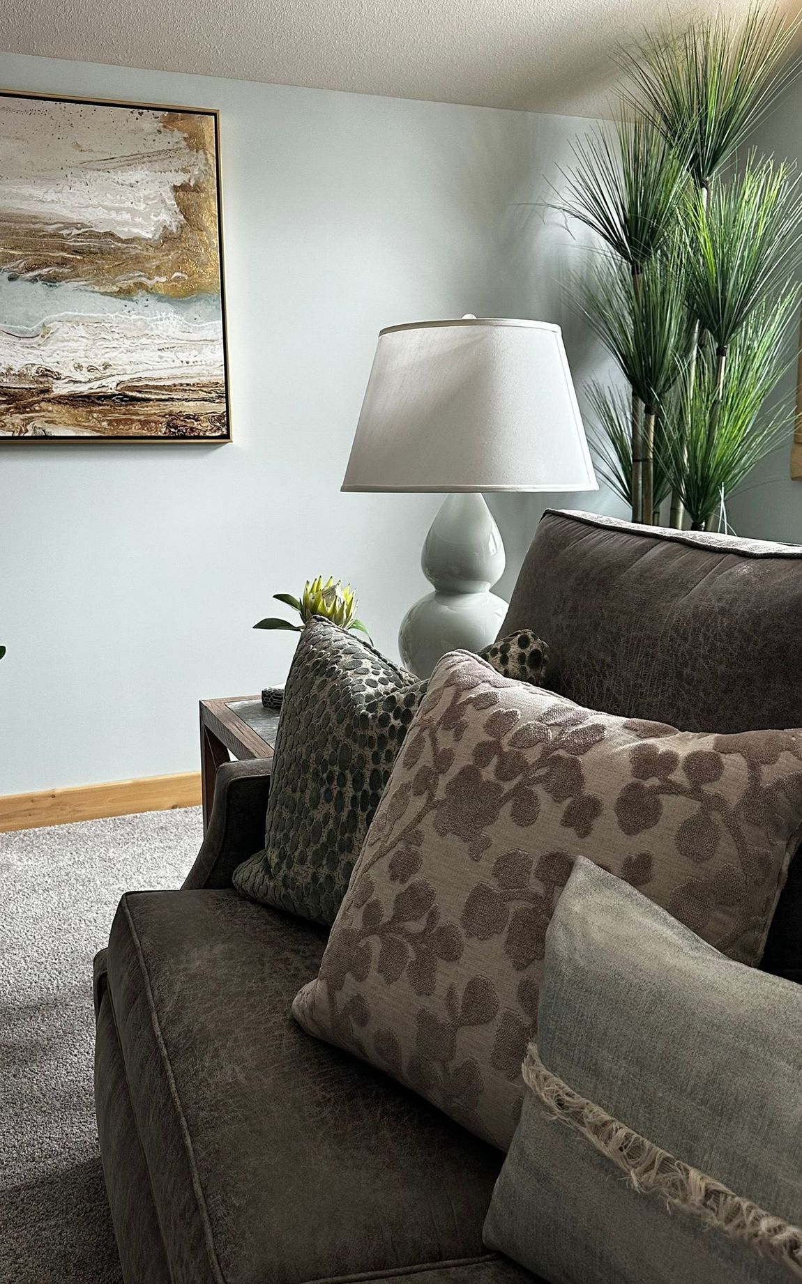 A living room with a couch , lamp , and painting on the wall.