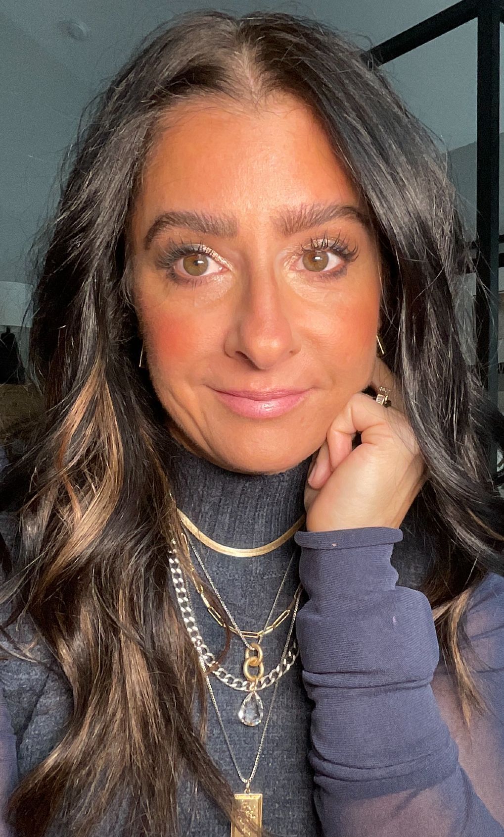 A close up of a woman wearing a turtleneck and necklaces.