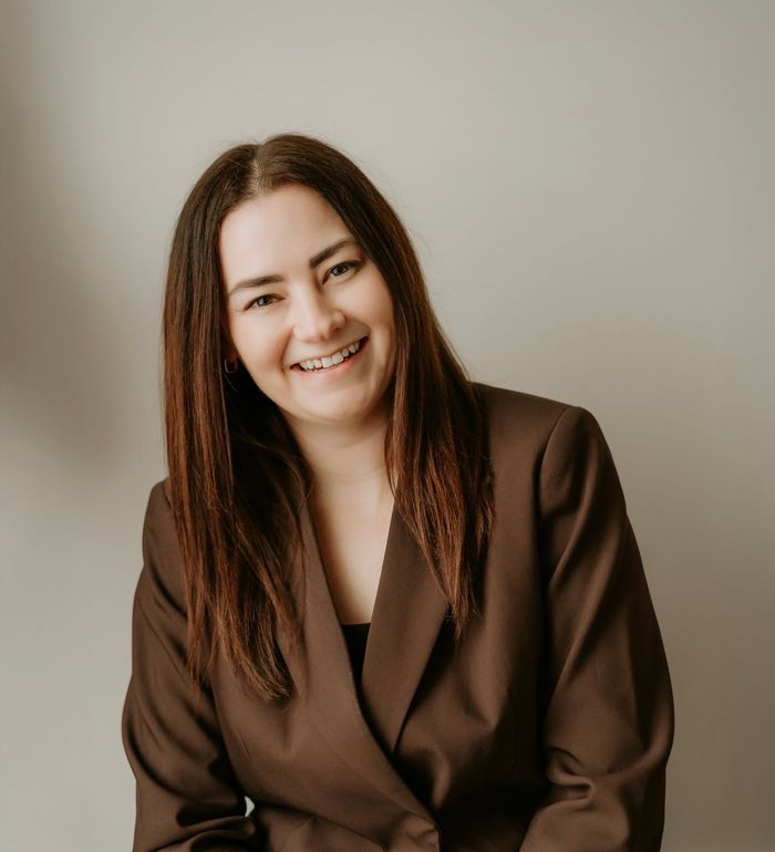 Friendly local cleaner Kim from Mo & Ko Clean sitting and smiling with cleaning supplies.