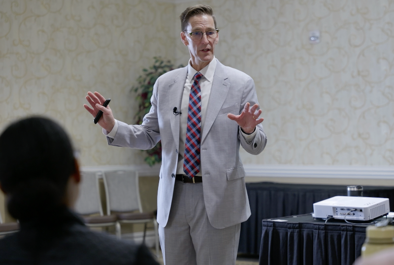 A man in a suit and tie is giving a presentation to a group of people.