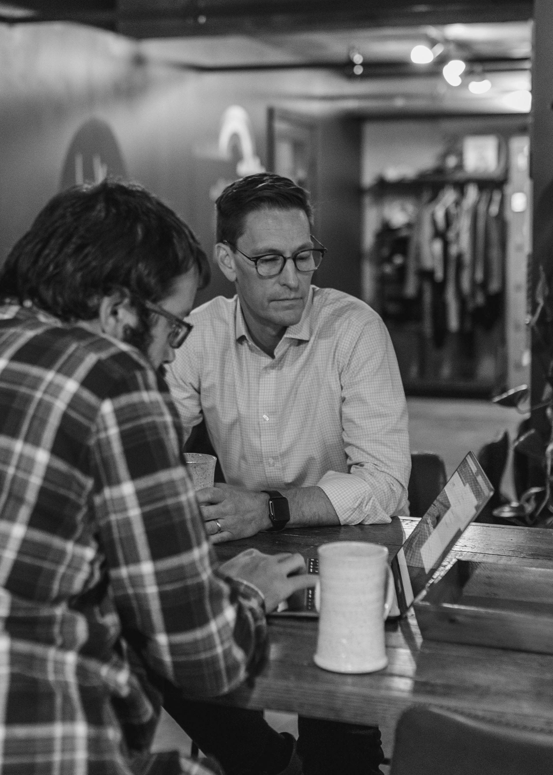 A black and white photo of two men sitting at a table.