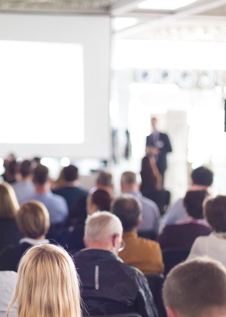 A group of people are sitting in a room watching a presentation.