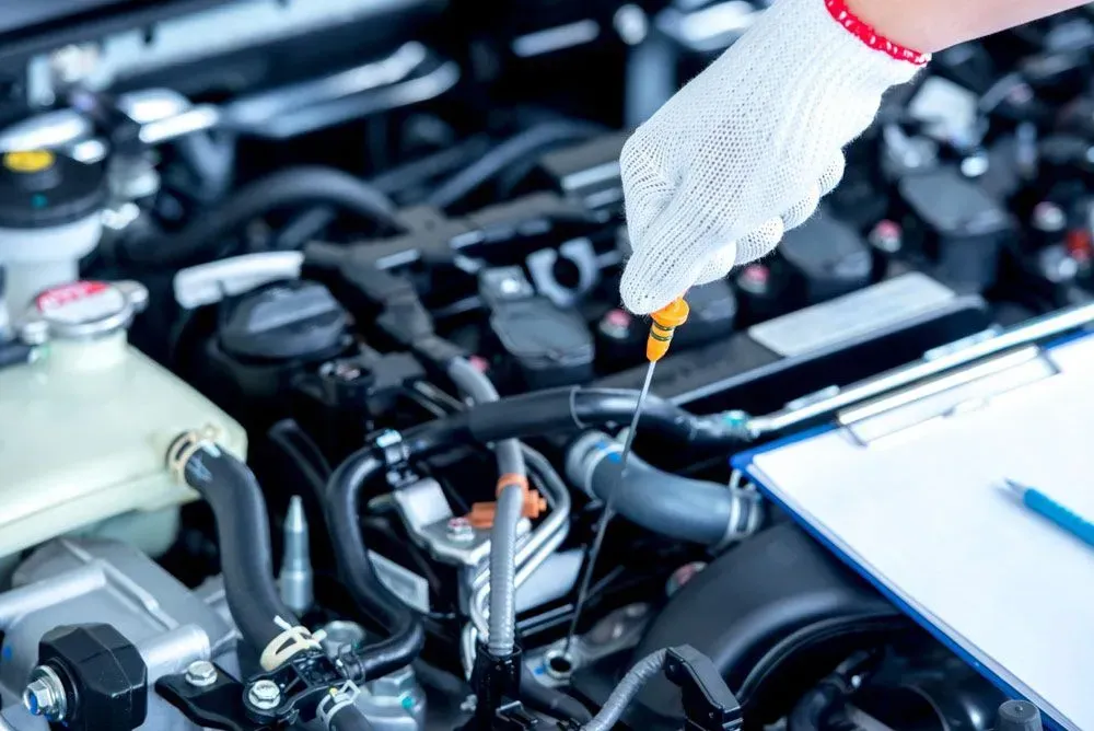 Mechanic Checking Engine Oil With Dipstick; Automotive Repair Setting — Carline Automotive and Exhausts in Belmont, NSW