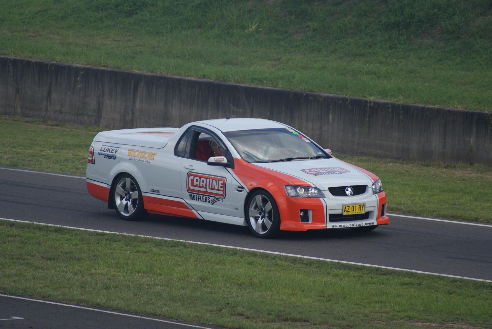 White and Orange Race Car Ute on a Track With Grass — Carline Automotive and Exhausts in Belmont, NSW