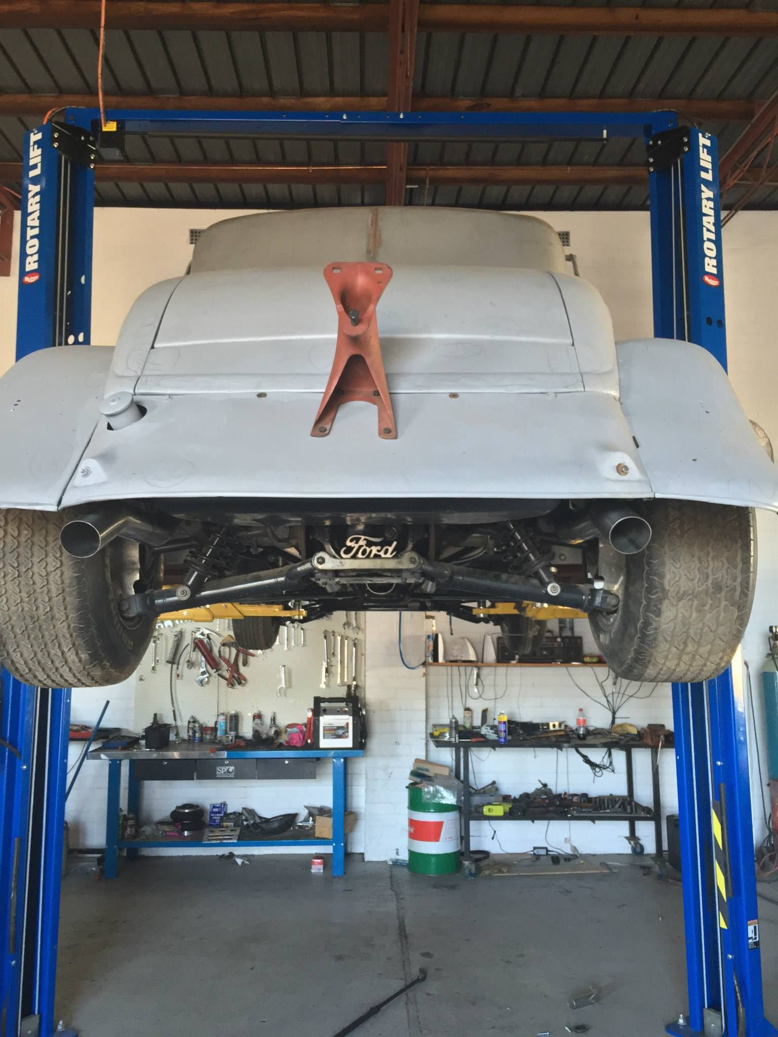 Underside Visible, Grey Body, Black Tires, Blue Lift. Workshop Setting — Carline Automotive and Exhausts in Belmont, NSW