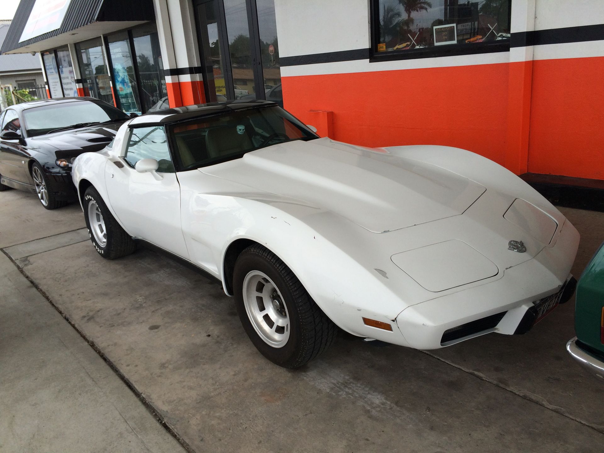 White Corvette parked outside a store with black and orange accents.