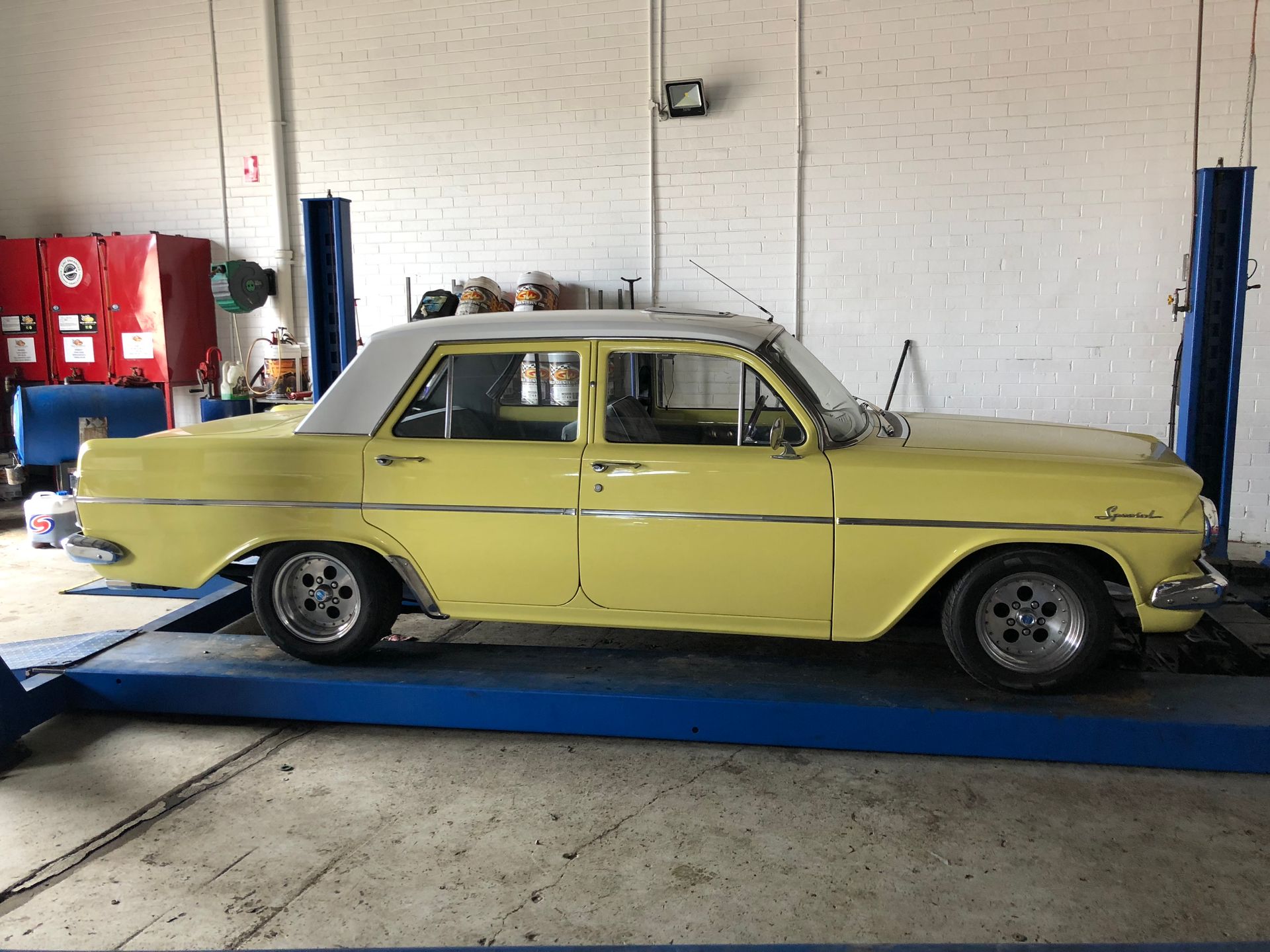 Yellow vintage car on a lift in a garage.