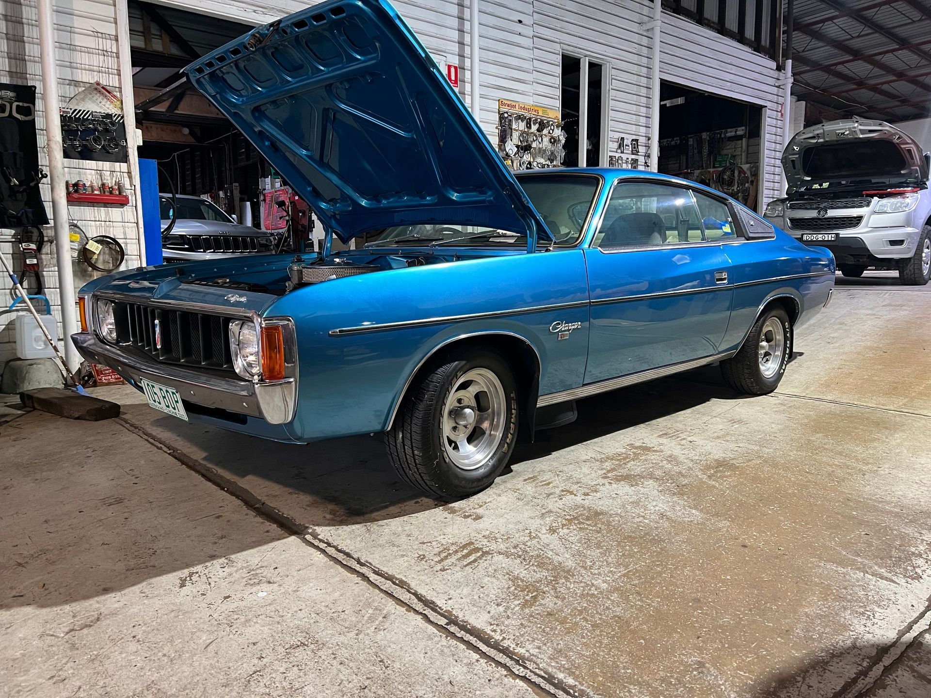 Blue classic car with hood up in a garage.