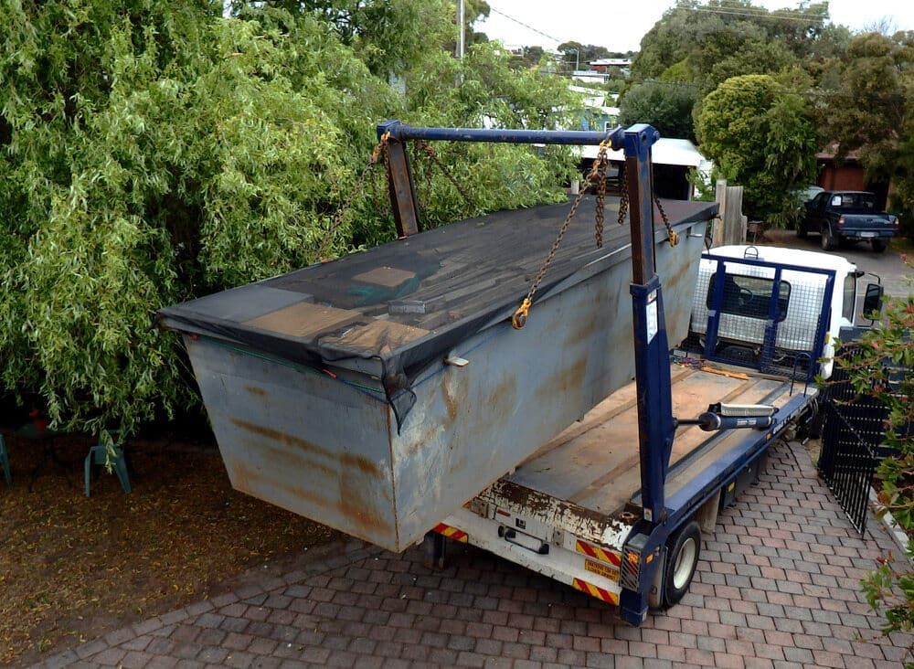 A Dumpster Is Sitting On The Back Of A Tow Truck — Little Mates Towing & Transport Pty Ltd In Yeppoon, QLD