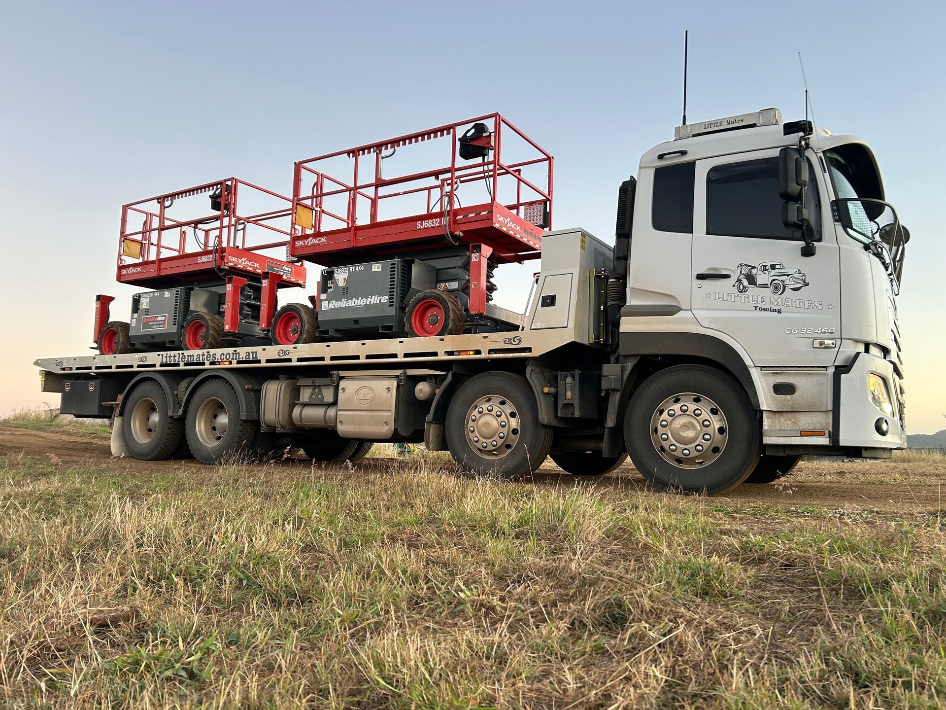 A Tow Truck Is Driving Down A Highway Carrying A Red Car — Little Mates Towing & Transport Pty Ltd In Emerald, QLD