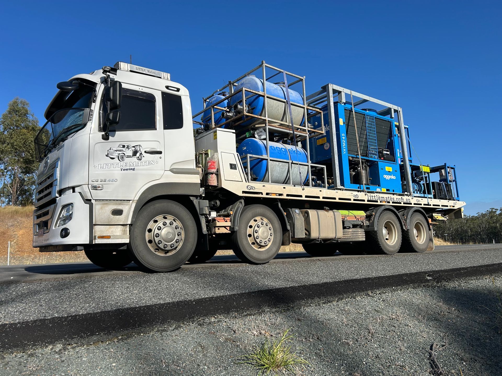 A Flatbed Truck Is Carrying An Excavator On The Back Of It — Little Mates Towing & Transport Pty Ltd In Yeppoon, QLD