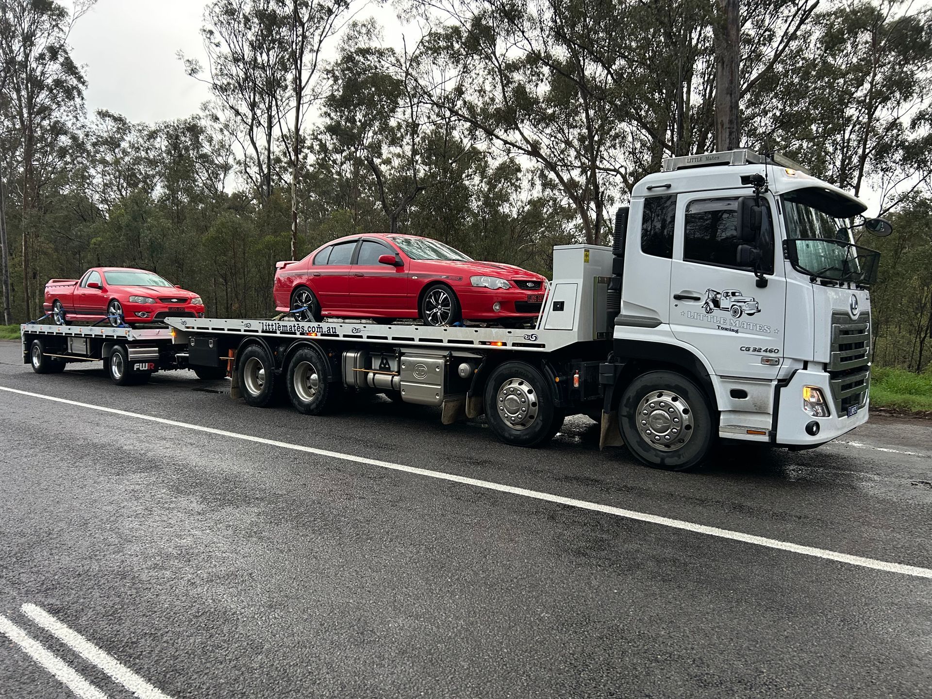 A Truck Is Carrying Two Vans On A Trailer On A Highway — Little Mates Towing & Transport Pty Ltd In Yeppoon, QLD