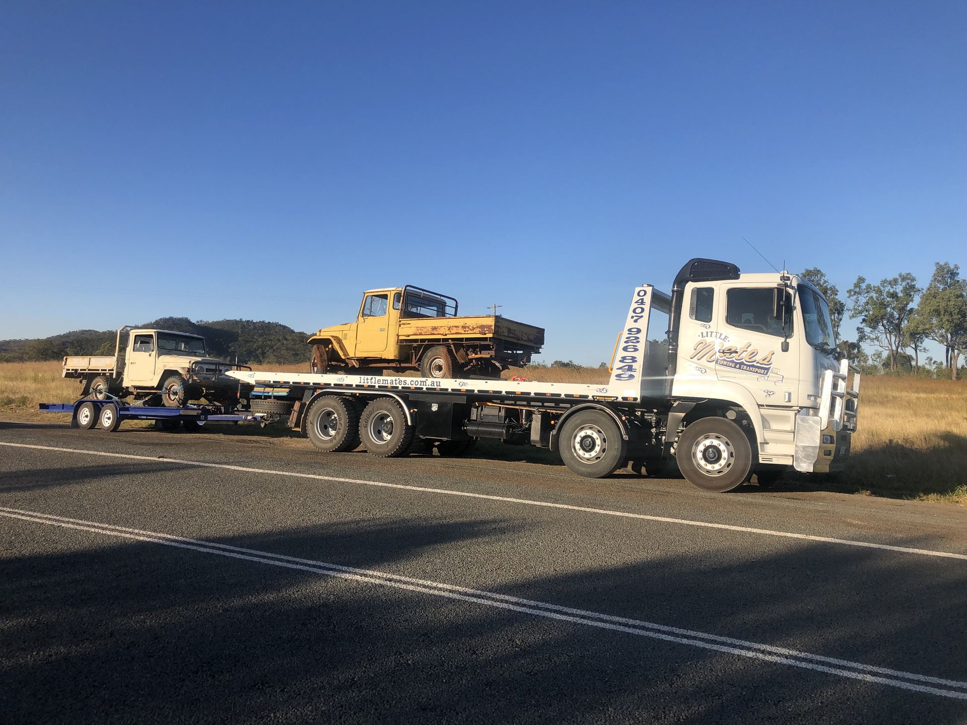 A Car Is Being Towed By A Tow Truck On The Side Of The Road — Little Mates Towing & Transport Pty Ltd In Glenlee, QLD