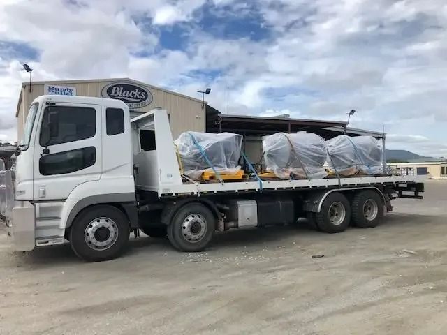 A White Truck With A Flat Bed Is Parked  In Front Of A Building — Little Mates Towing & Transport Pty Ltd In Glenlee, QLD