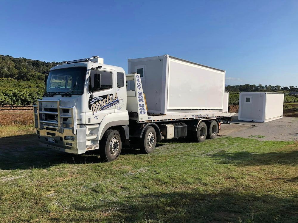 A White Truck With A Container On The Back Is Parked In A Field — Little Mates Towing & Transport Pty Ltd In Glenlee, QLD