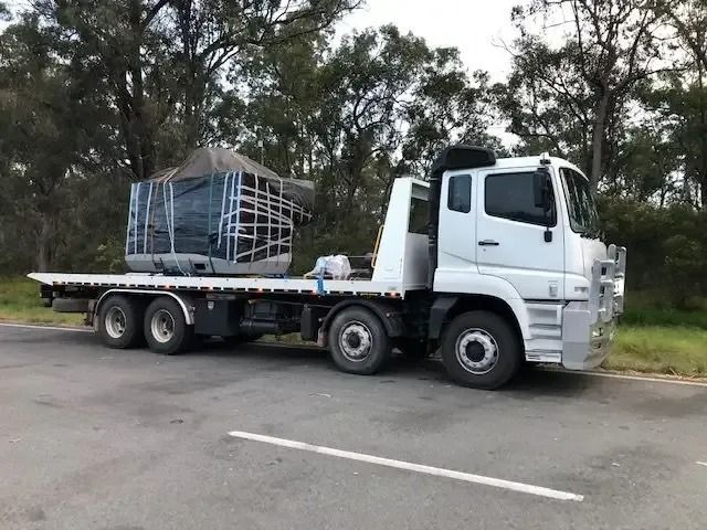 A White Flatbed Truck Is Parked On The Side Of The Road — Little Mates Towing & Transport Pty Ltd In Gladstone, QLD