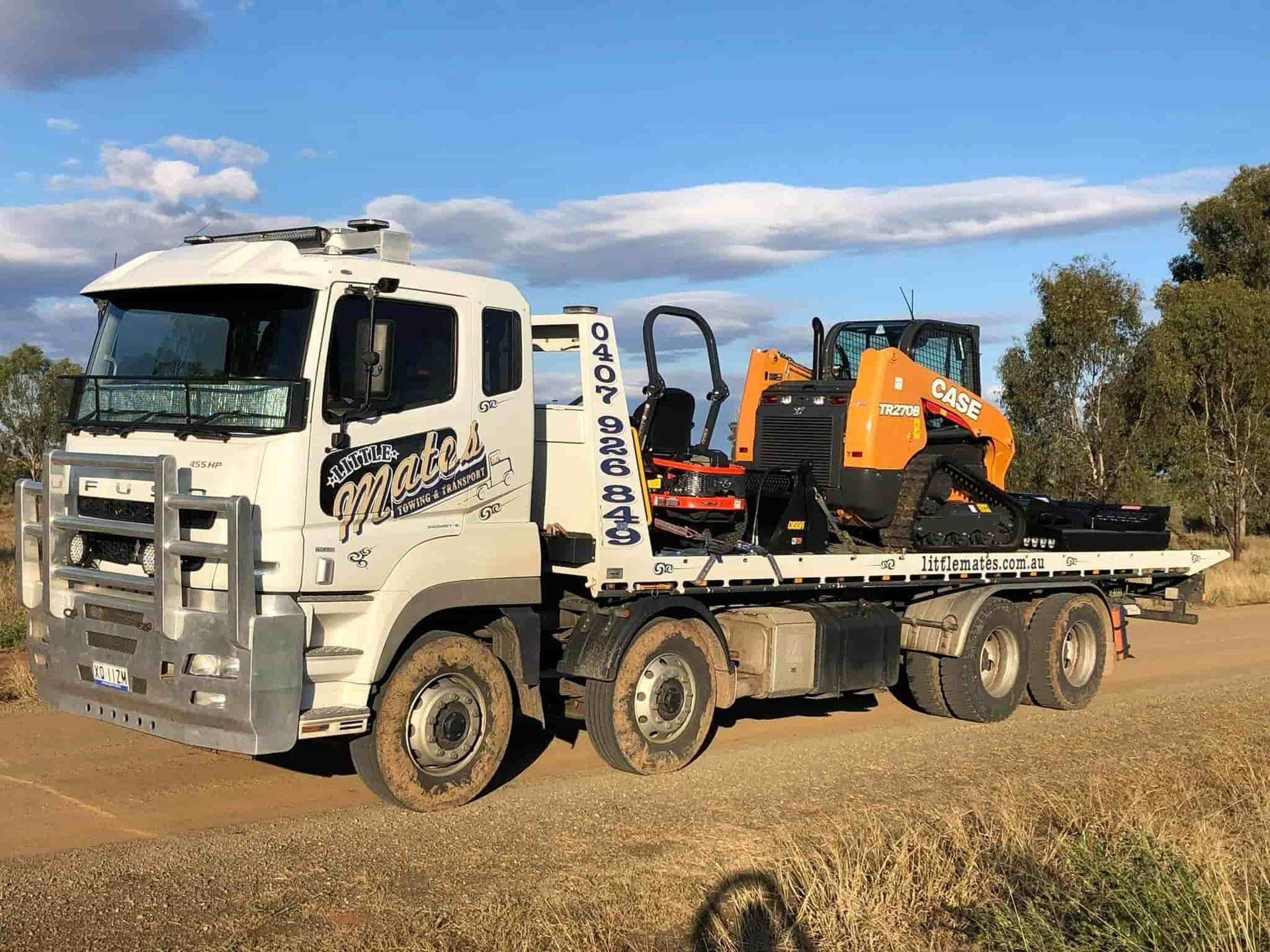 A Tow Truck With A Tractor On The Back Is Parked On A Dirt Road — Little Mates Towing & Transport Pty Ltd In Glenlee, QLD