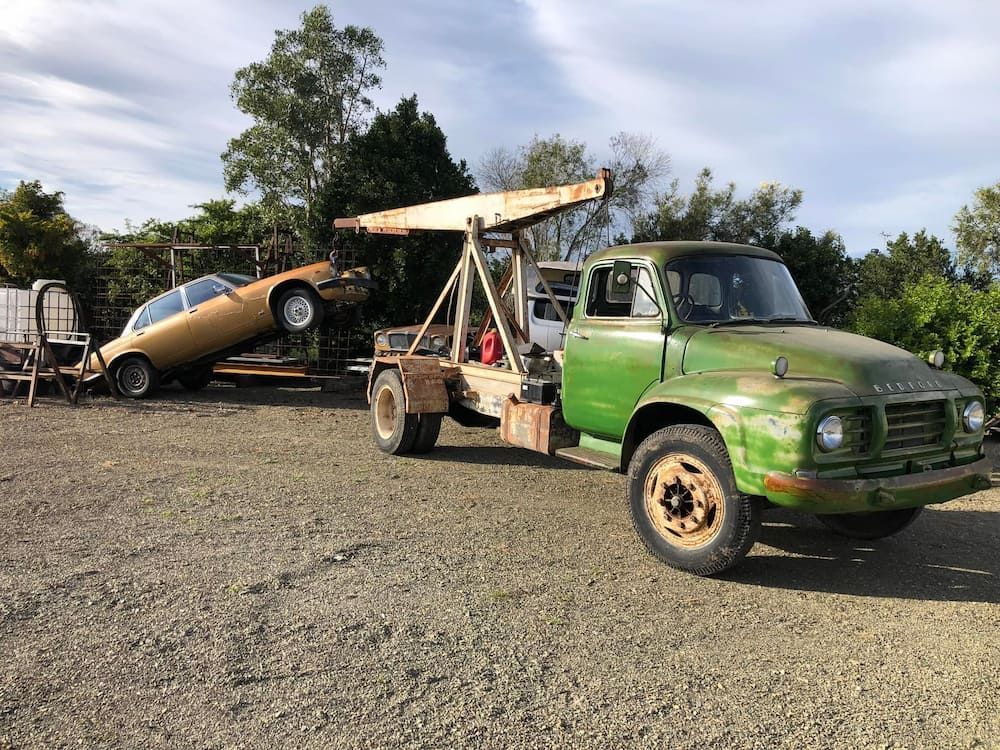 A Green Tow Truck Is Carrying A Car On A Trailer — Little Mates Towing & Transport Pty Ltd In Glenlee, QLD