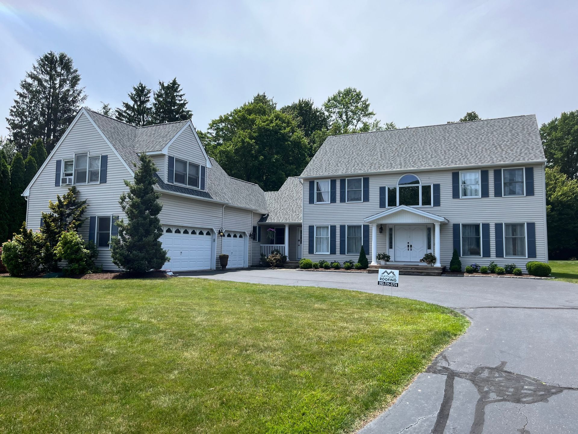Roof with gray shingles, blue dormer with a white-framed window against a blue sky.