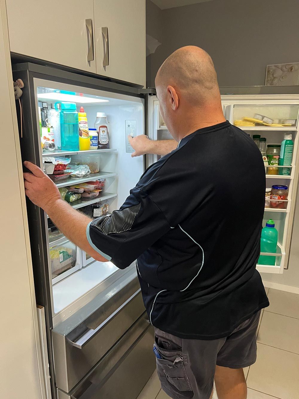 Man Checking Fridge - Appliance Repairs in Taree, NSW