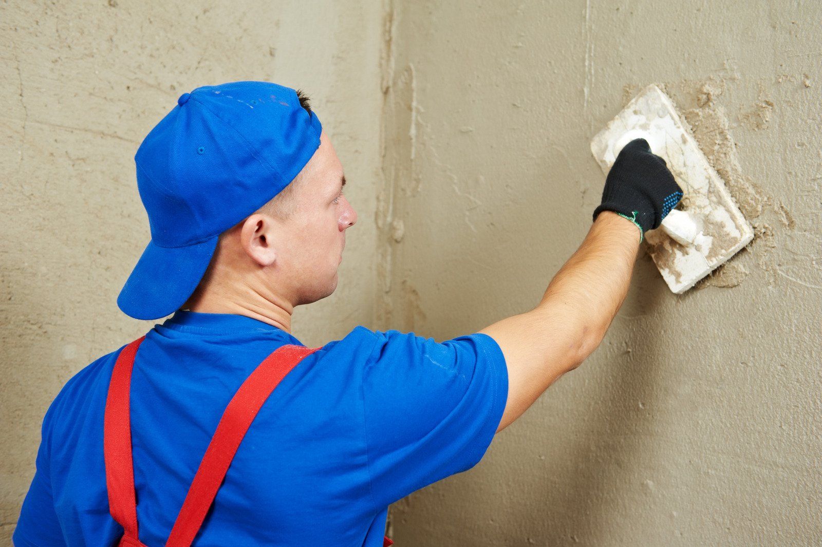 A man is plastering a wall with a trowel.