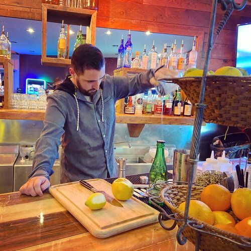 A man is cutting lemons on a cutting board in a restaurant