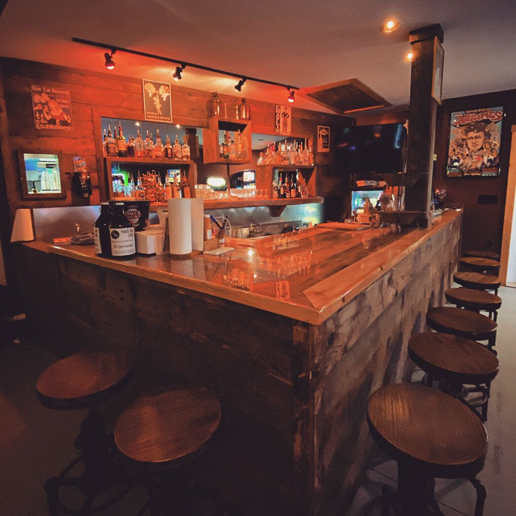 A bar with stools and bottles on the counter