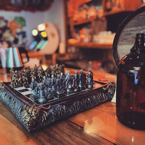 A chess board is sitting on a wooden table next to a bottle