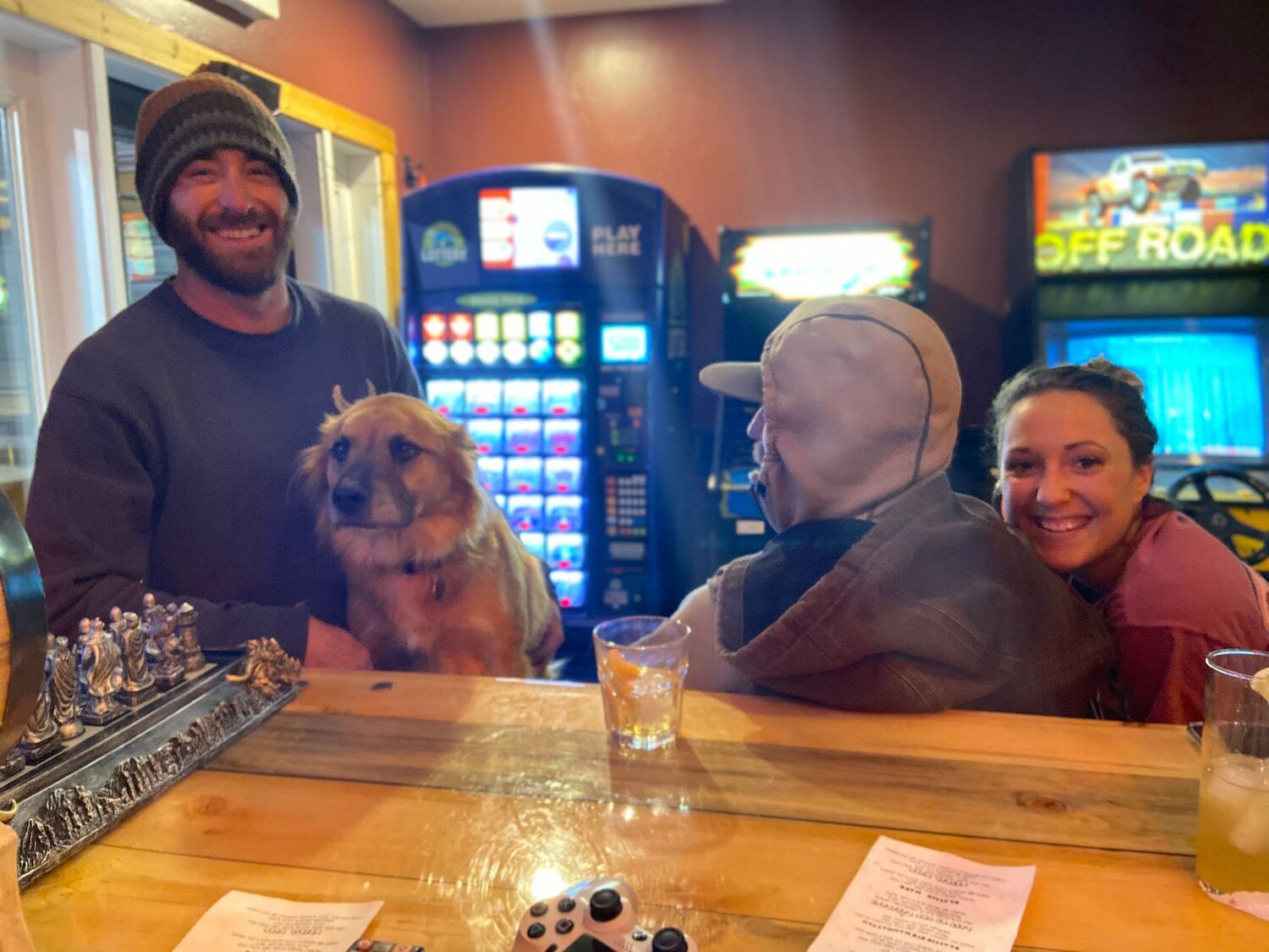 A man and a woman are sitting at a bar with a dog.