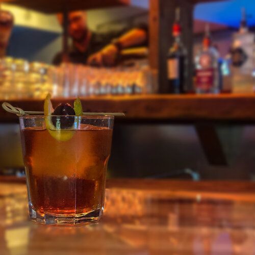 A close up of a drink in a glass on a table in a bar.