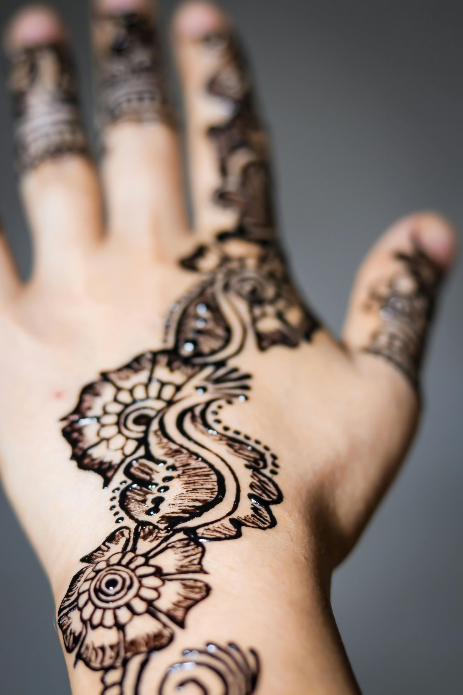 Hand with intricate henna design in dark brown.