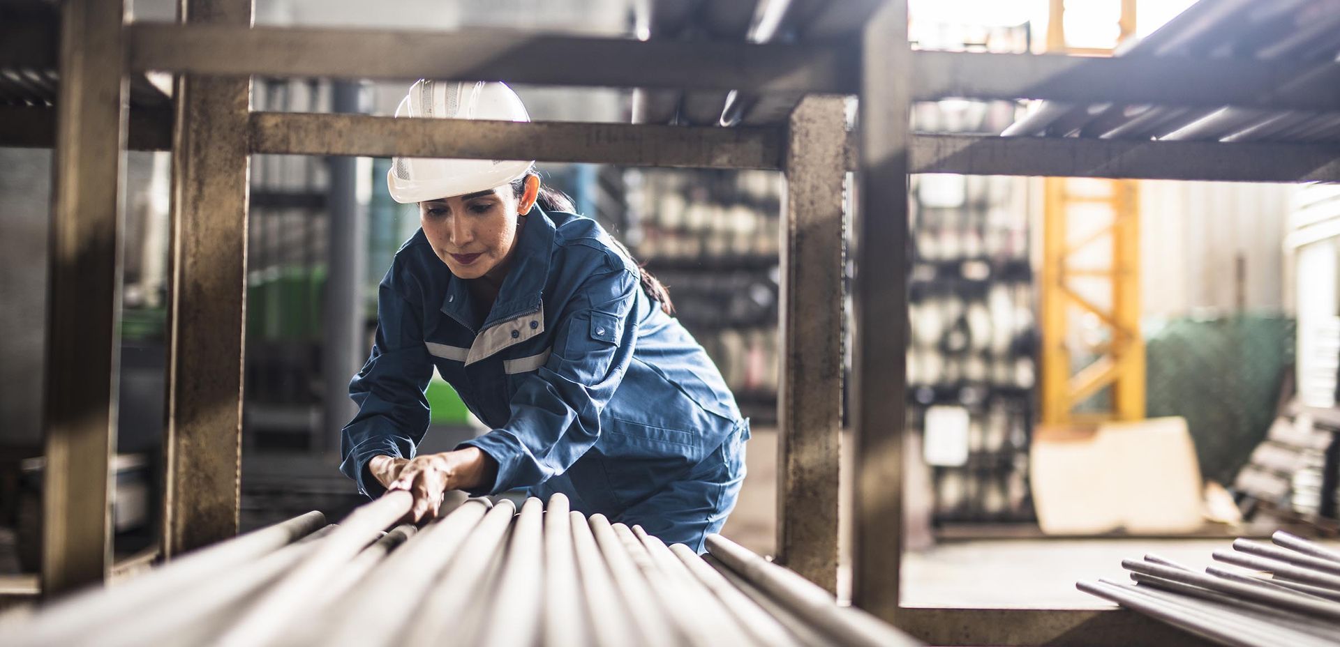 A man is working on a stack of metal pipes in a factory.