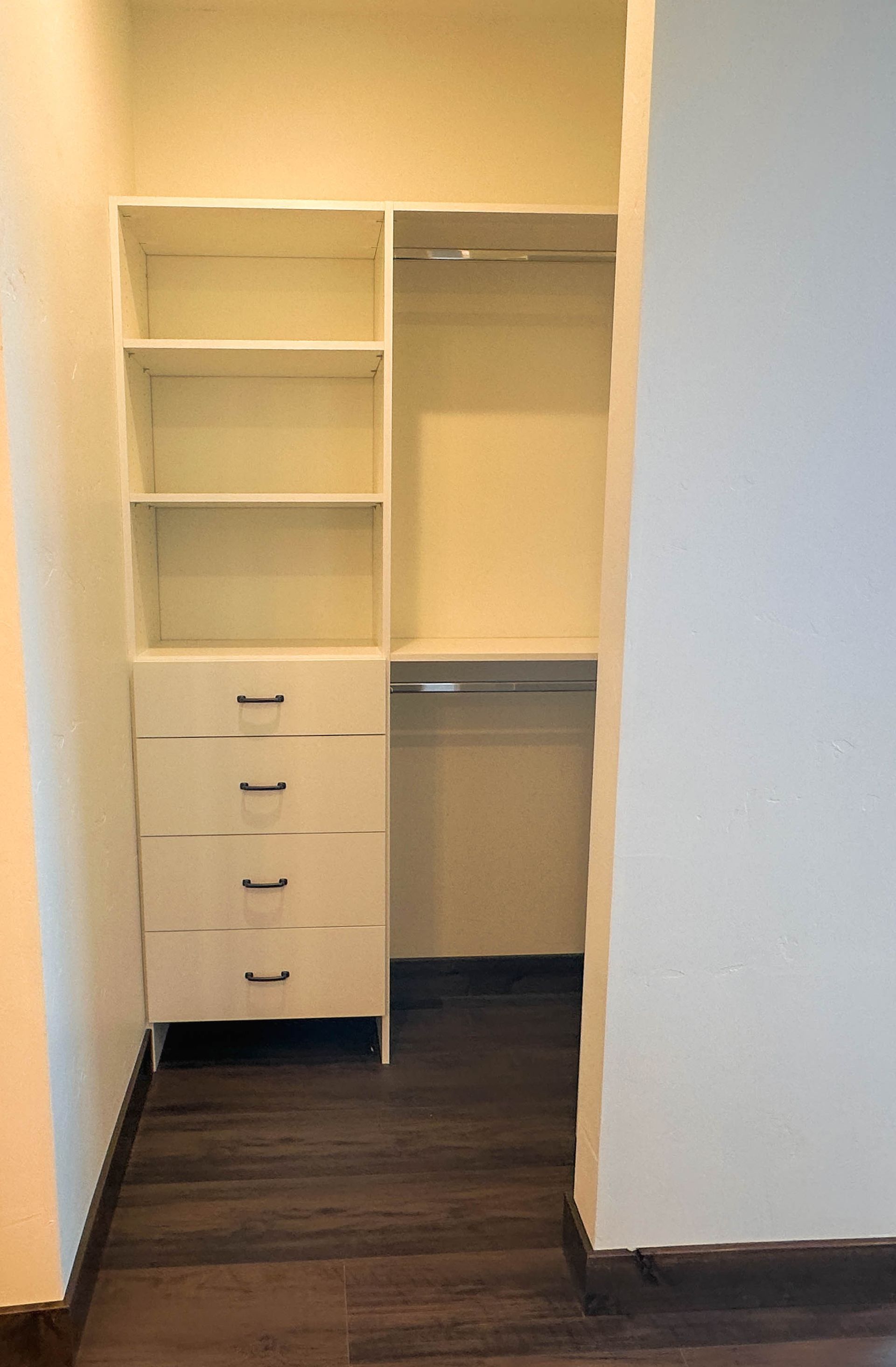 a walk in closet with white shelves and drawers