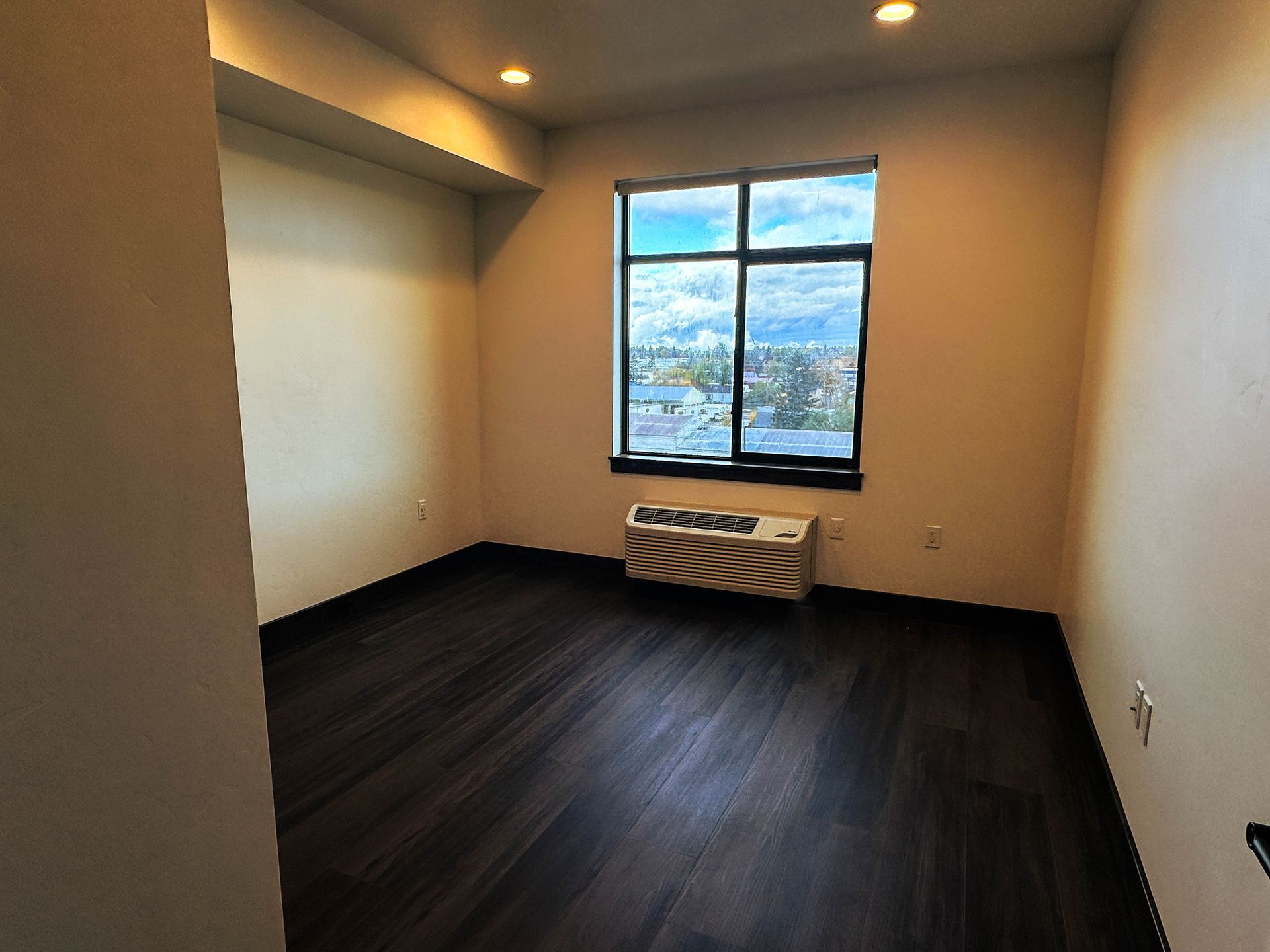 an empty room with a window and a small air conditioner