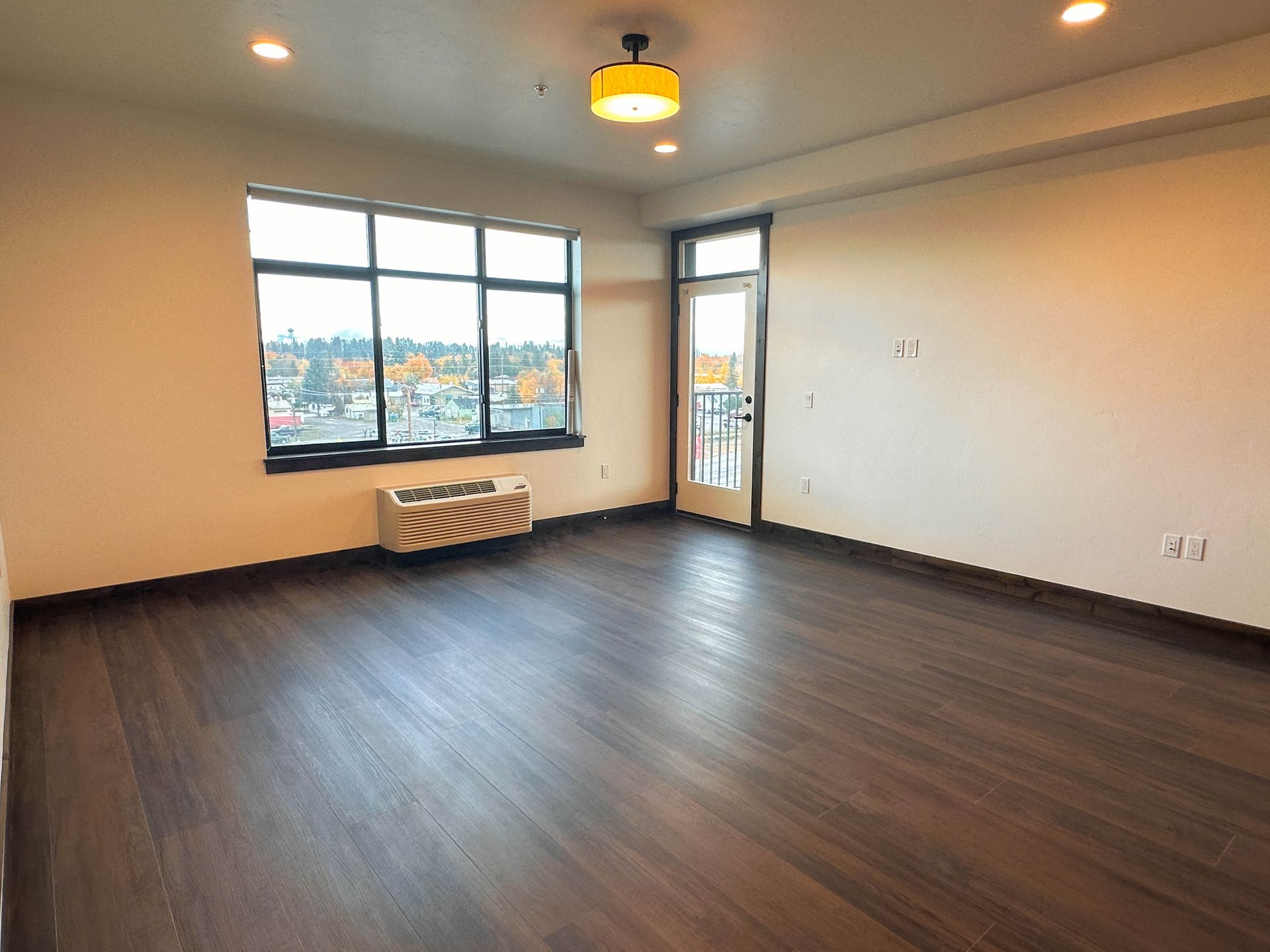 an empty room with a window and a small air conditioner