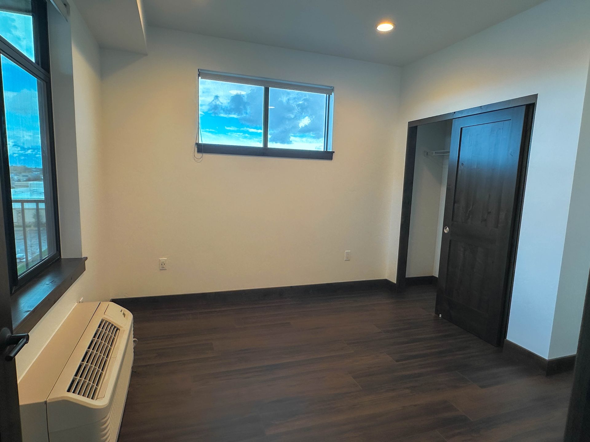 an empty room with a window and a small air conditioner