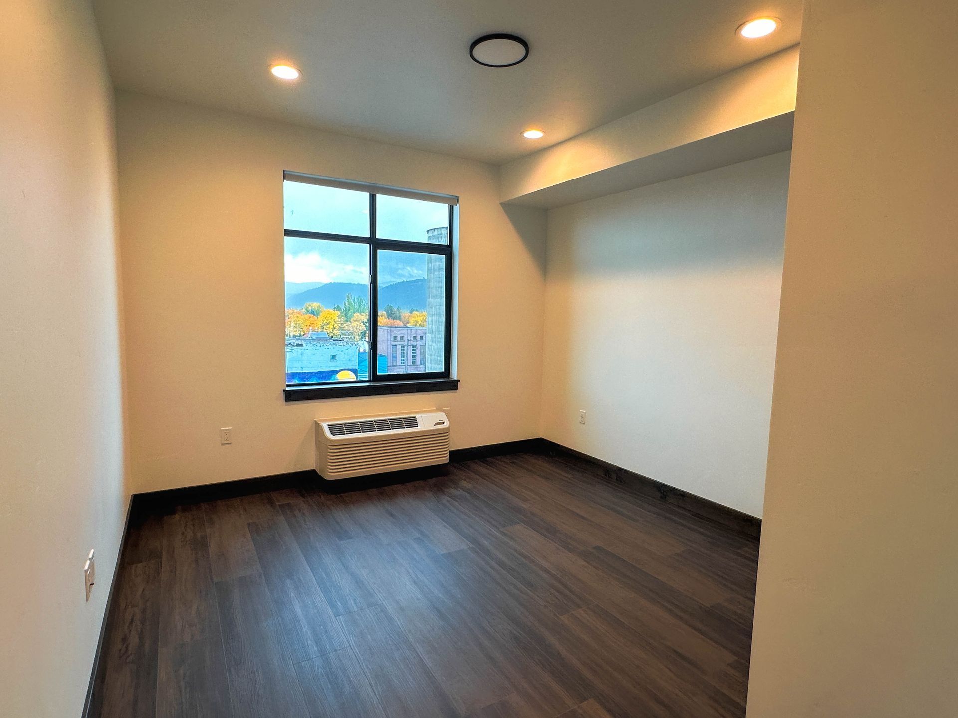 an empty room with a window and a small air conditioner