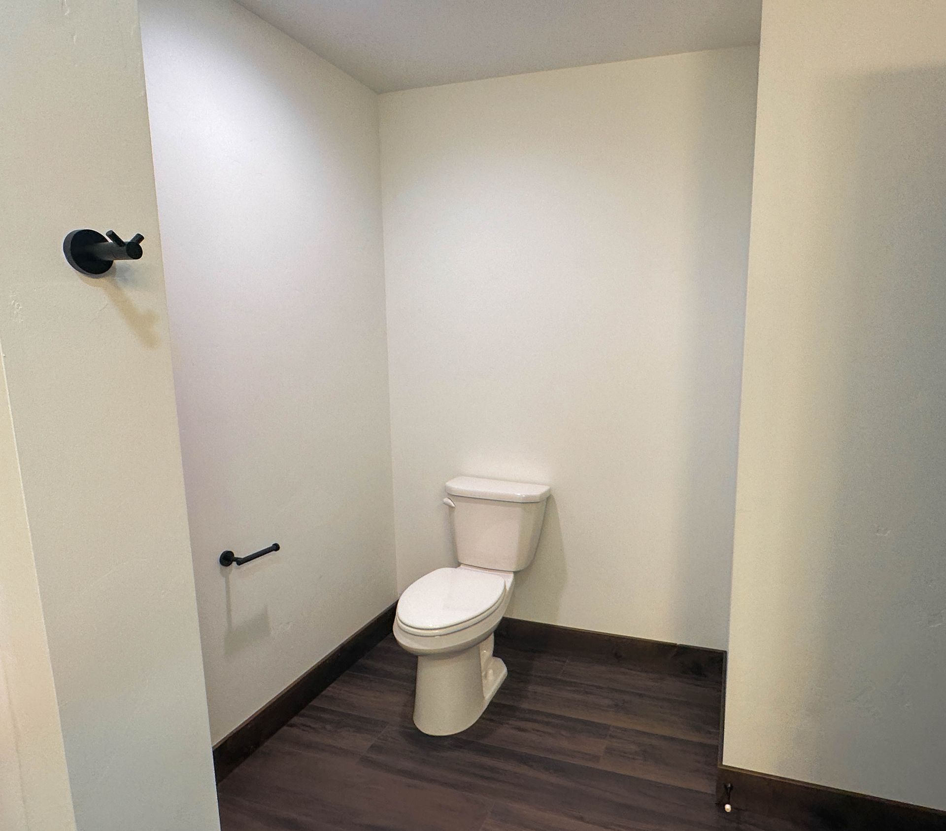 an empty bathroom with a toilet and a hook on the wall