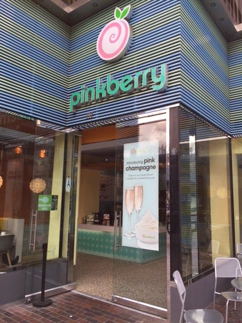 The outside of a pinkberry restaurant with tables and chairs
