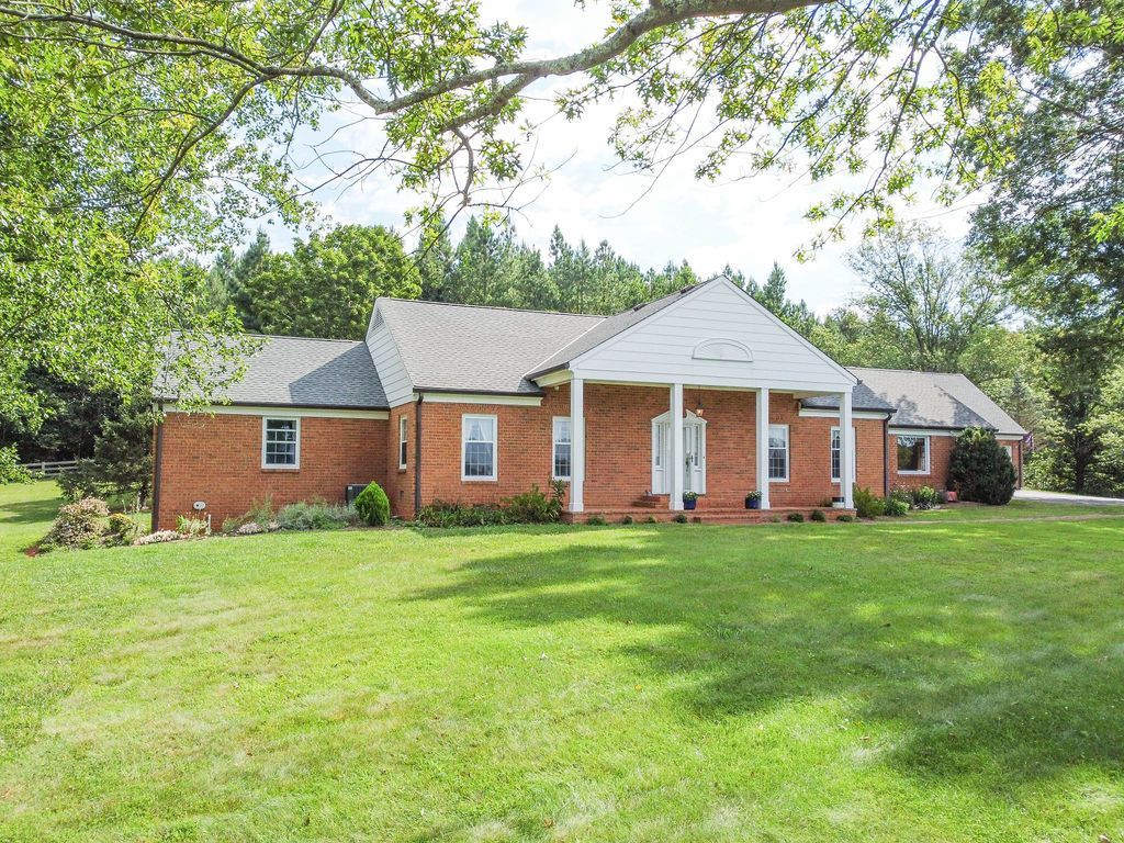 A large brick house with a large lawn in front of it.
